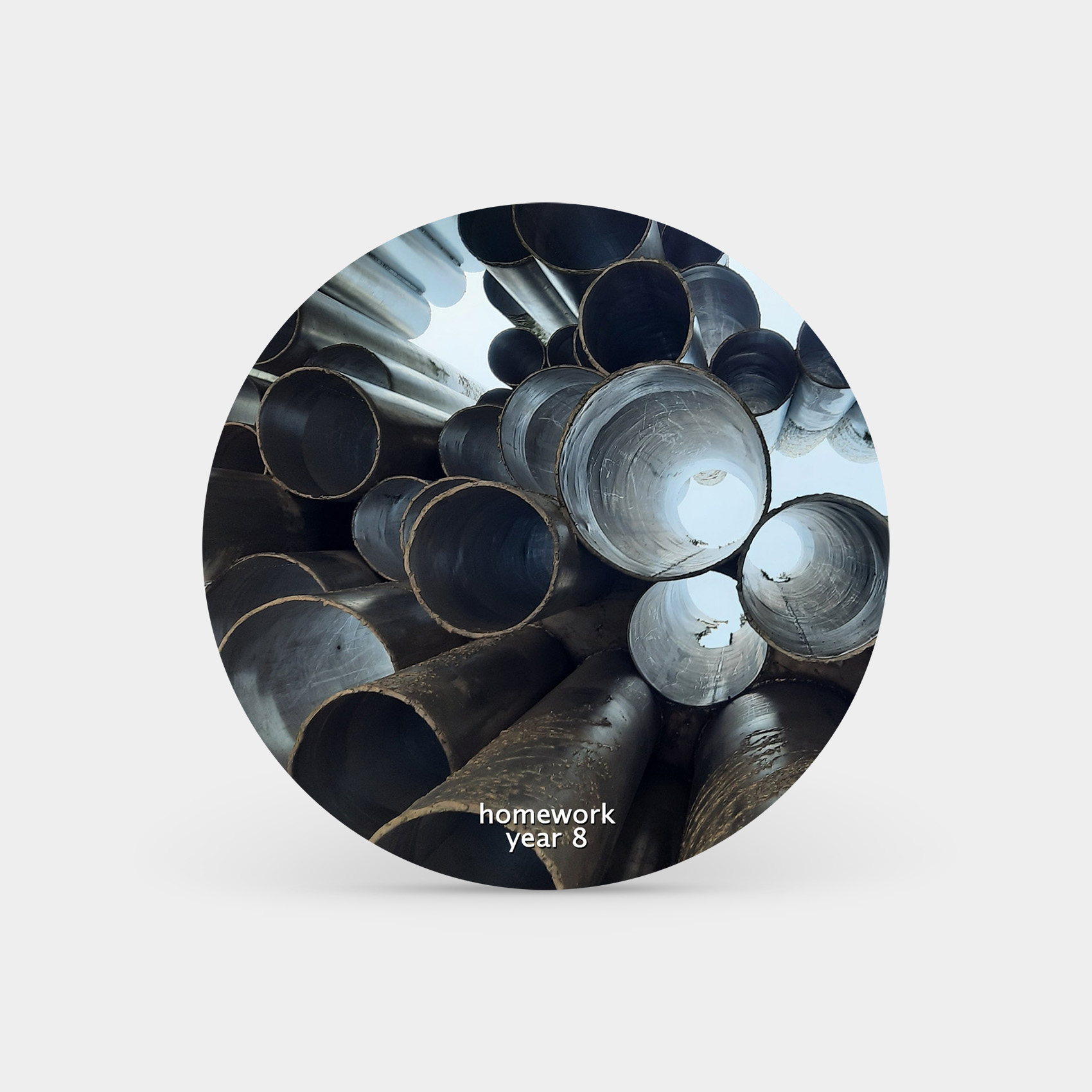 Circle floating in grey space with a slight shadow underneath to make it look like it’s standing upright. The circle has a photo looking through a pile of metal pipes with light on the other side shining through. At the bottom of the circle there is white text that reads: homework - year 8.